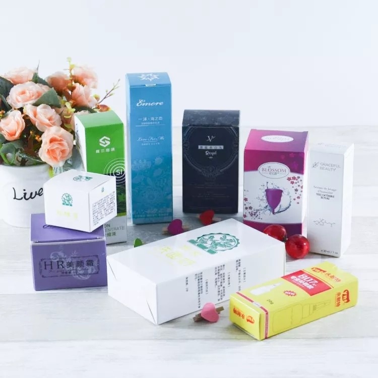 Le panneau en ivoire imprimé polychrome enferme dans une boîte les boîtes blanches de carton de cosmétiques de soin de la peau